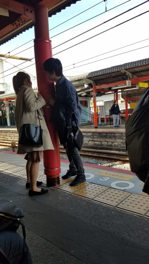 Young couple playing a game at a train station in Kyoto - Train travel people-watching