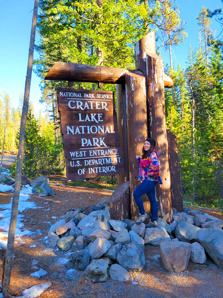 Linds standing in front of the west entrance sign to Crater Lake National Park