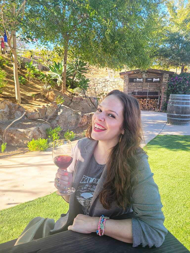 Linds smiling outdoors with glass of red wine in hand - Cheers to wine for the holidays