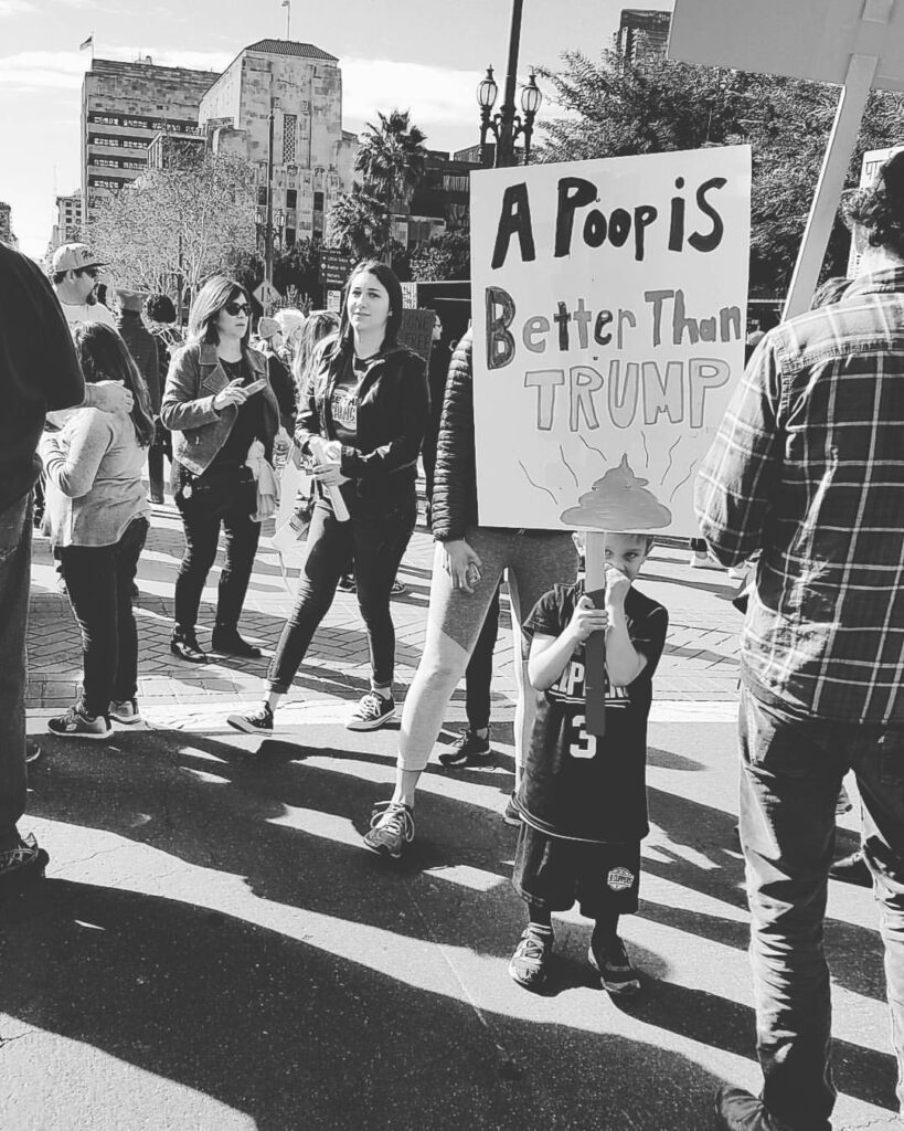 Little boy holding a sign that reads: A Poop Is Better Than Trump