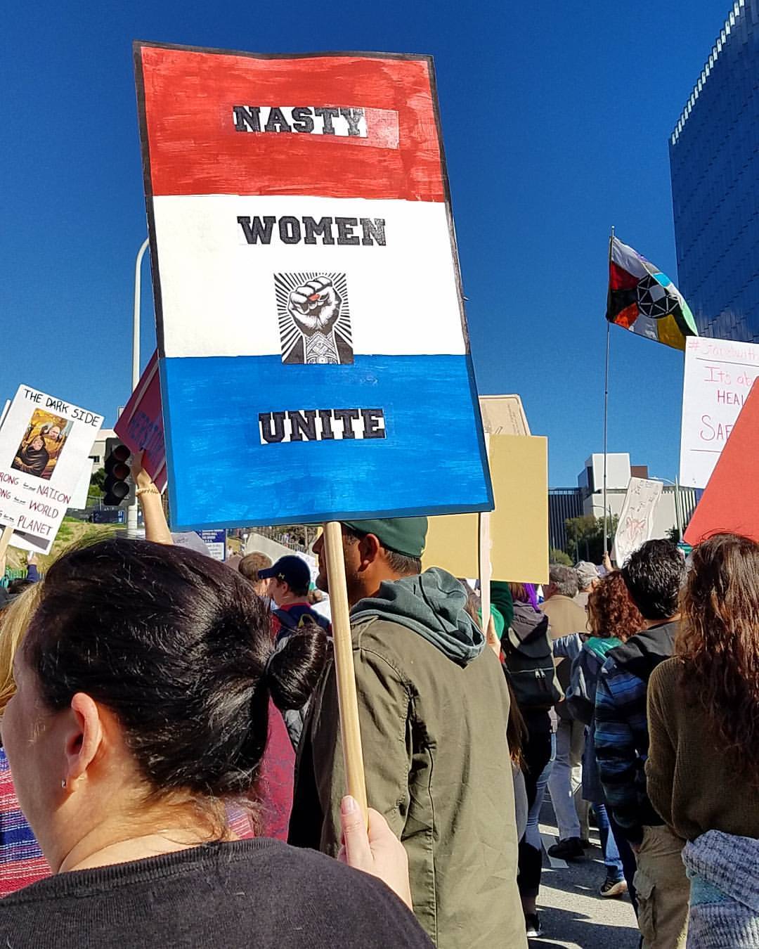 sign that reads: NASTY WOMEN UNITE International Women's Day March