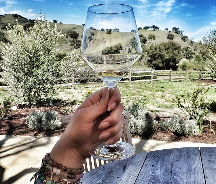 Linds holding her wine glass up with nature in the background