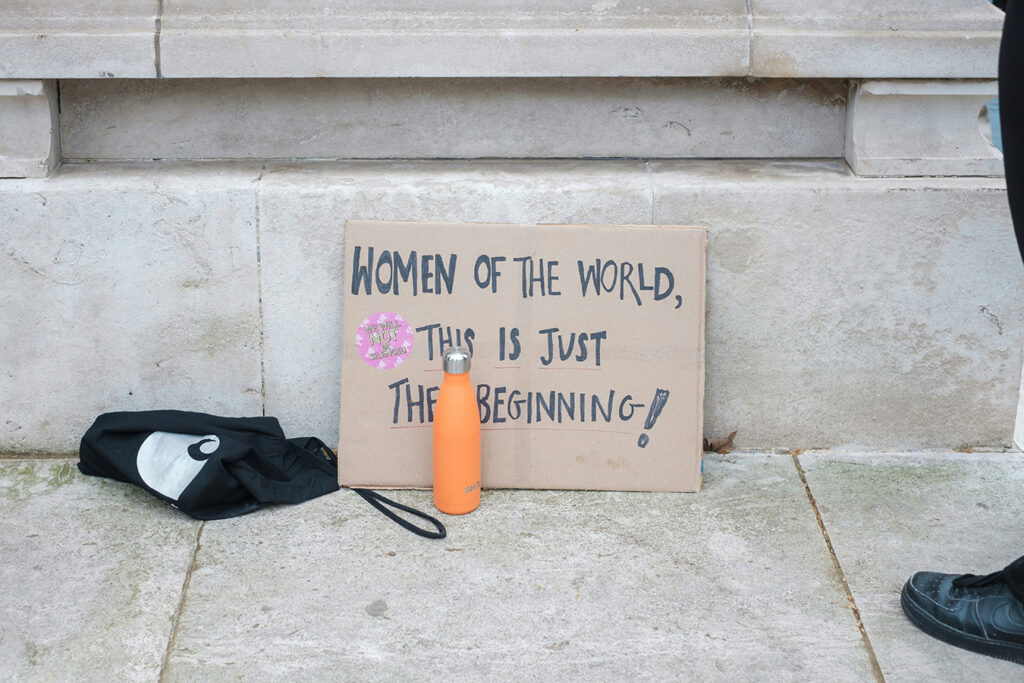 cardboard sign that reads: Women of the world, this is just the beginningInternational Women's Day PSA