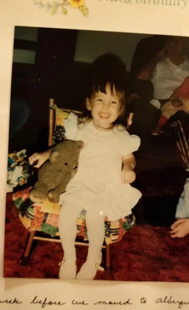 LIL' KASEY HERRIN sitting in rocking chair with stuffed teddy bear
