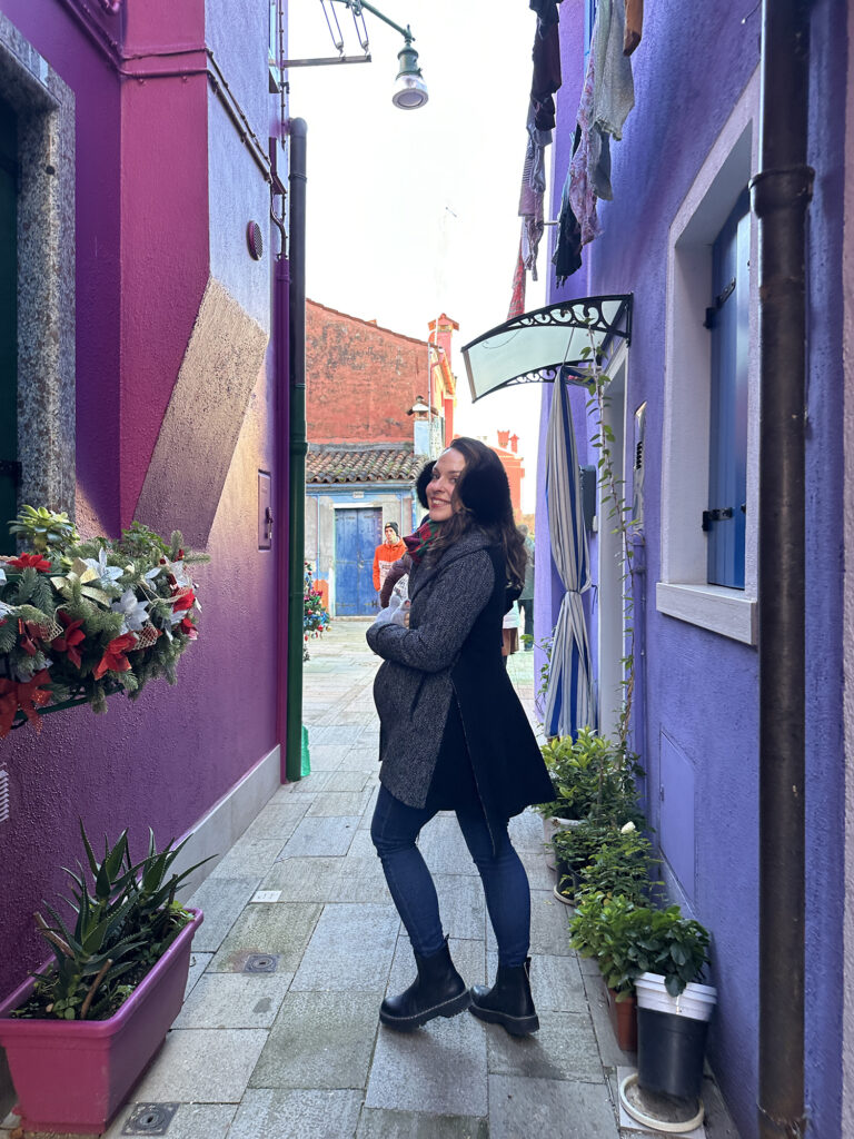 Linds on Burano island in a narrow alleyway with colorful buildings on either side